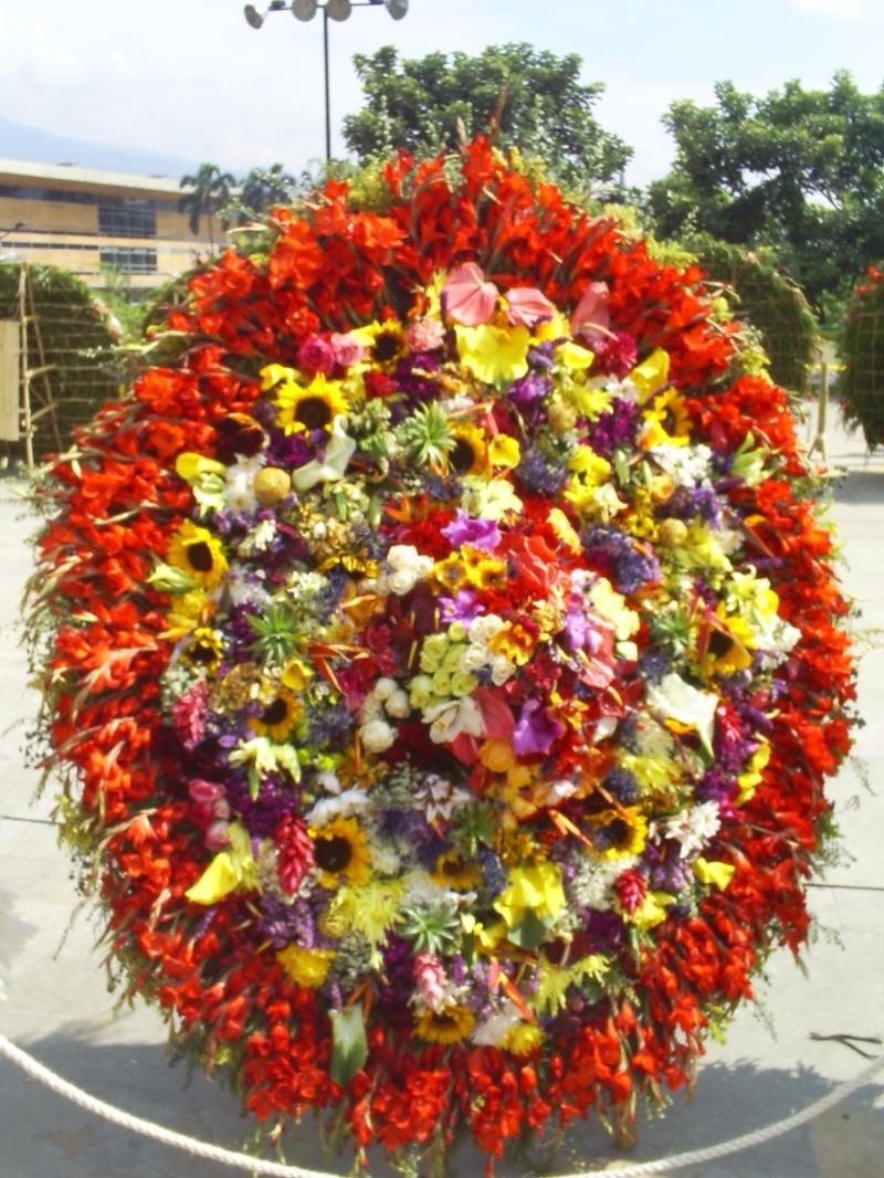 A traditional round silleta packed with red gladioli, sunflowers, roses and orchids on display in Medellín