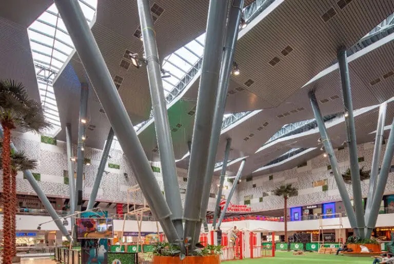 Mayorca's tall atrium with slanted steel columns, skylights and palm trees above an open central floor
